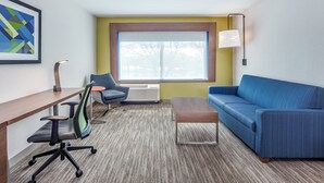 Une chambre d’hôtel moderne avec une grande fenêtre, un canapé bleu, un bureau en bois, une chaise et une lampe.