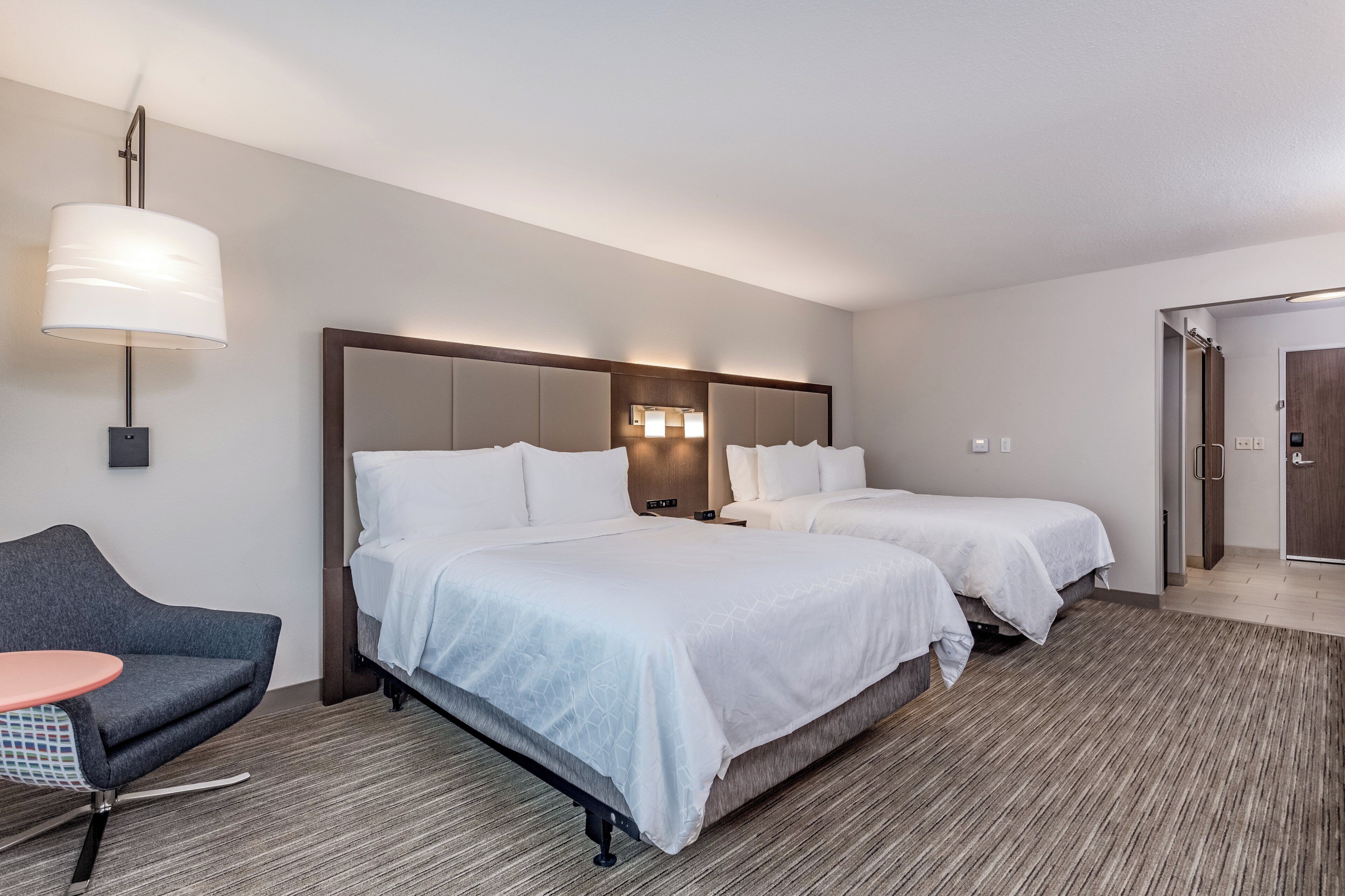 Une chambre d’hôtel avec deux lits, un canapé, une lampe et un miroir.
