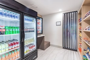 Habitación limpia y moderna con refrigerador lleno de bebidas, un bar de aperitivos y vista al exterior.