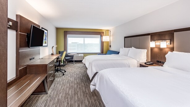 Une chambre d’hôtel avec deux lits, un bureau avec une chaise, une télévision et une fenêtre donnant sur un paysage agréable.