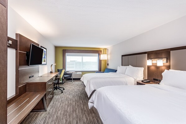 A hotel room with two beds, a desk with a chair, a TV, and a window with a view.