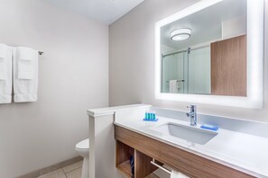 A modern bathroom with a white sink, a mirror, and a glass shower enclosure.