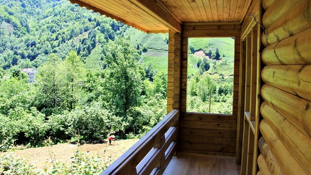 Una cabaña de madera con balcón que da a un exuberante valle verde.