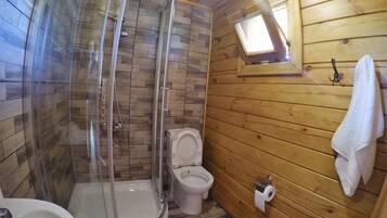 Puisesta mökistä löytyy kylpyhuone, jossa on lasiseinällä varustettu suihku, wc ja pesuallas.