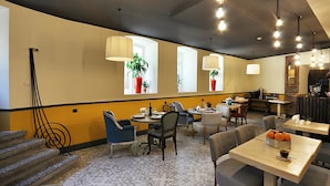A modern dining area with multiple tables and chairs, potted plants, and a staircase.
