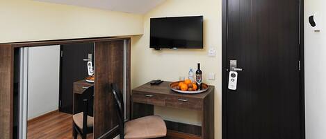Una habitación compacta con escritorio, silla y televisor montado en la pared.