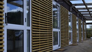 Un edificio moderno con ventanas amplias y listones de madera en el exterior.