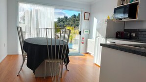 Una cocina moderna con microondas, cafetera y un refrigerador pequeño. Hay un comedor con mesa y sillas.