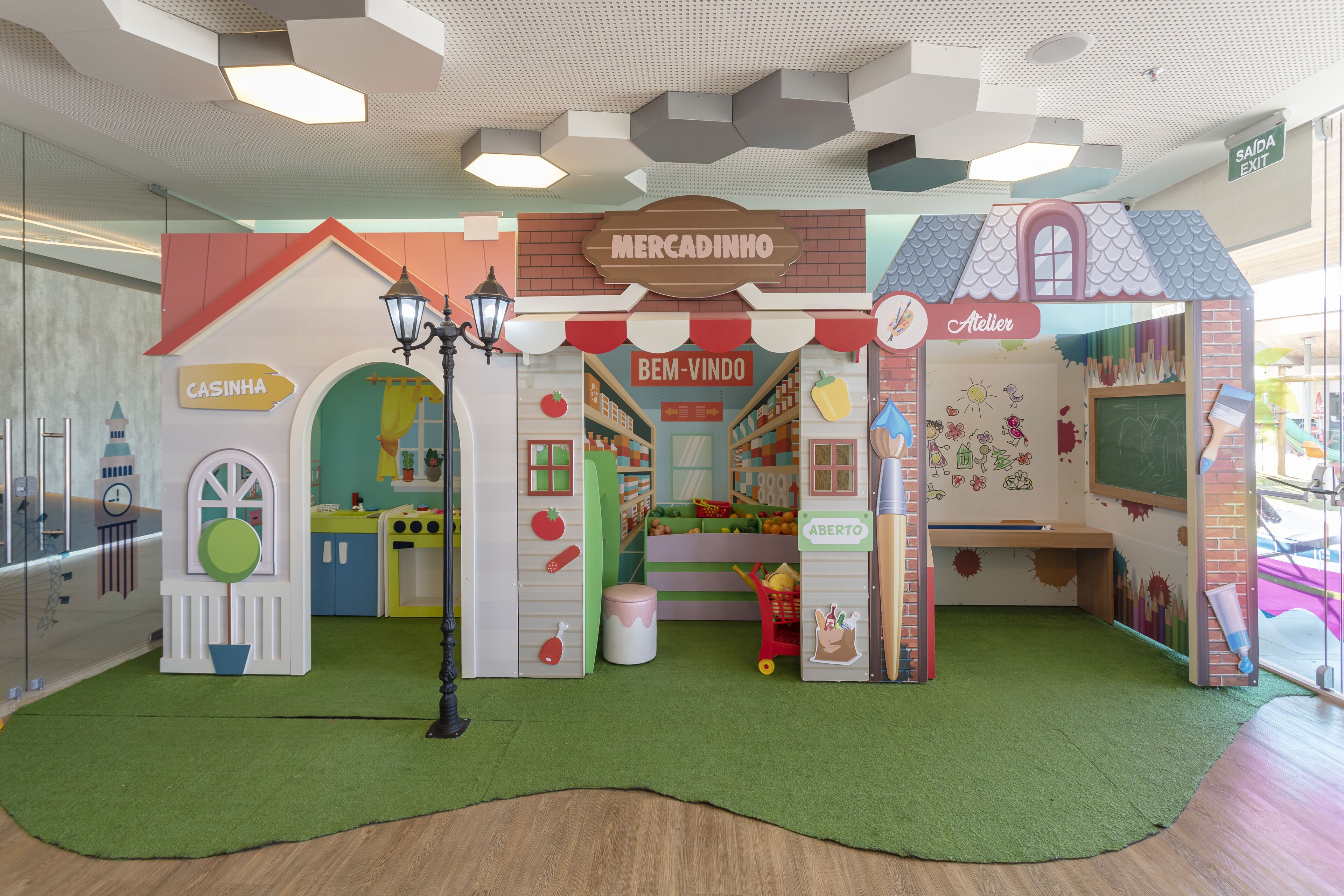 A children's play area with a market theme, including a bakery, a café, and a toy store.