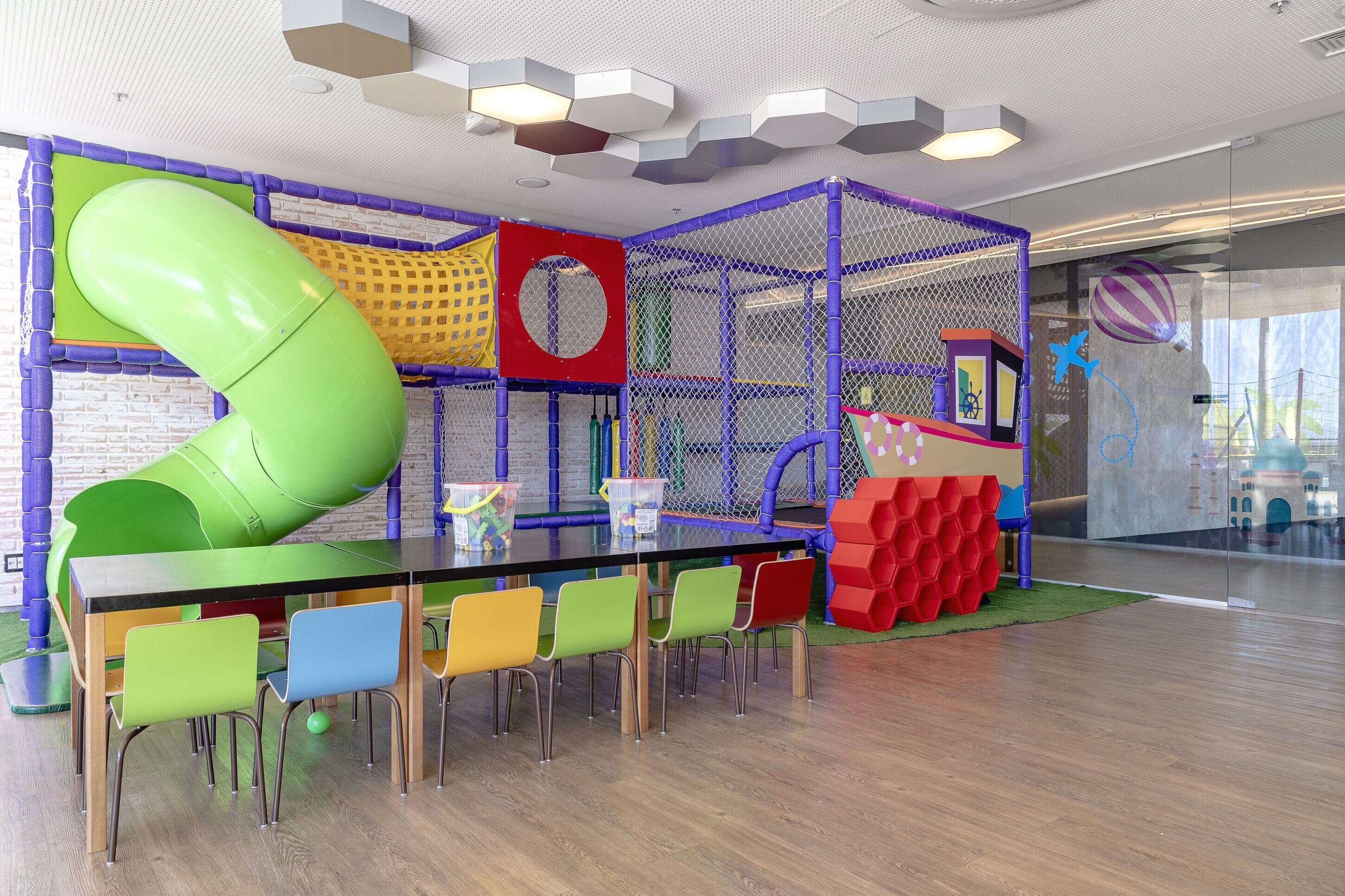 A play area with a green slide, a climbing wall, and a play structure.