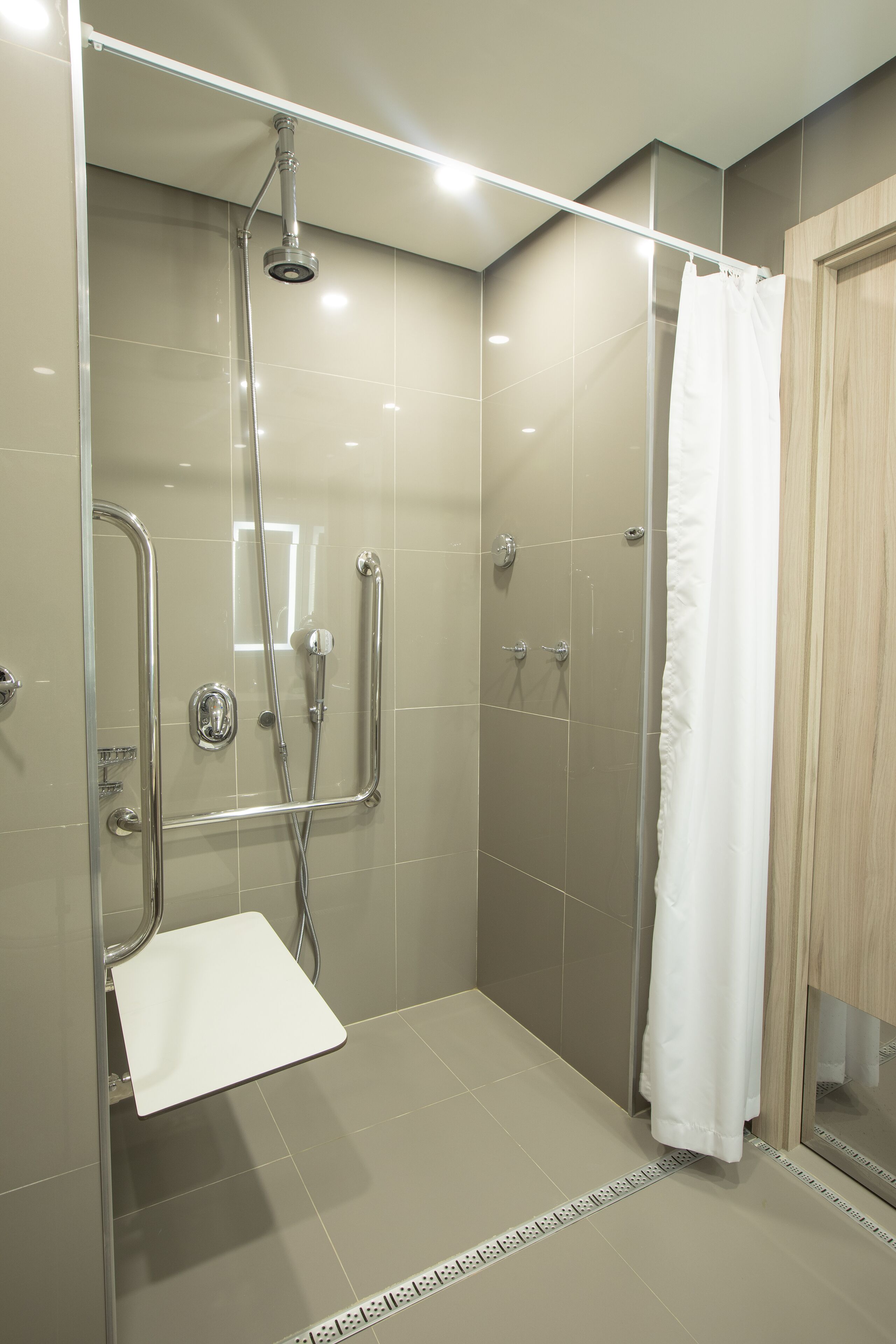 A modern shower area with a glass door, a white towel, and a shower control panel.