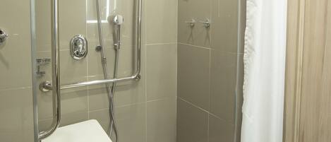 A modern shower area with a glass door, a white towel, and a shower control panel.