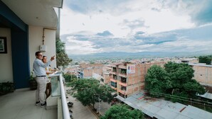 Un balcon offrant une vue sur le paysage urbain, avec des bâtiments et des arbres.
