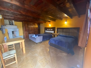 Habitación con dos camas, un escritorio de madera, una silla, chimenea y piso de baldosas.