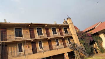 Un edificio de varios pisos con balcones, una escalera y una antena parabólica.