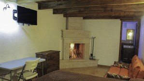 A room with a fireplace, a desk, a chair, and a bed with orange pillows. - Hotel Kuautli (Huasca de Ocampo)