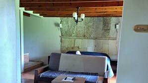 A cozy living area with a stone fireplace, a wooden bench, and a small table. - Hotel Kuautli (Huasca de Ocampo)