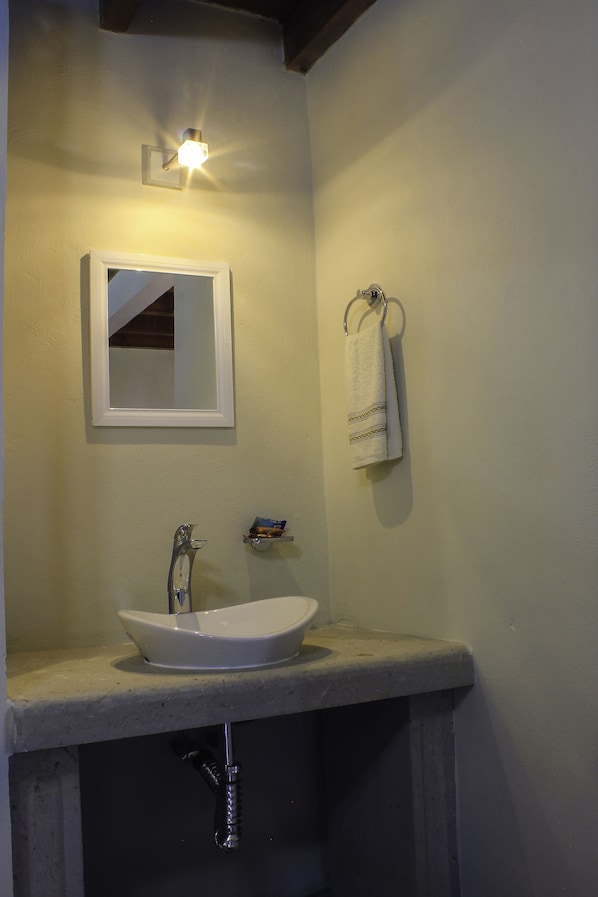 A bathroom with a white sink, a mirror, and a towel hanging on a rack.