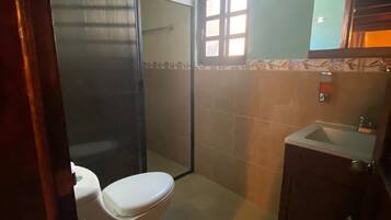 Un baño pequeño con inodoro, lavamanos y cabina de ducha.
