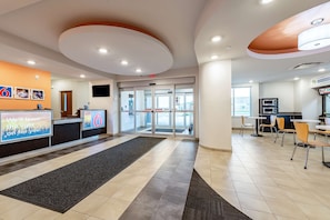 Welcome to our lobby, featuring a reception desk, revolving doors, and a comfortable seating area.