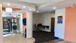 A modern lobby with a vending machine, seating area, and a reception desk.