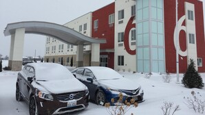 A hotel with a large '6' on the facade, two cars parked in front, and a covered entrance.