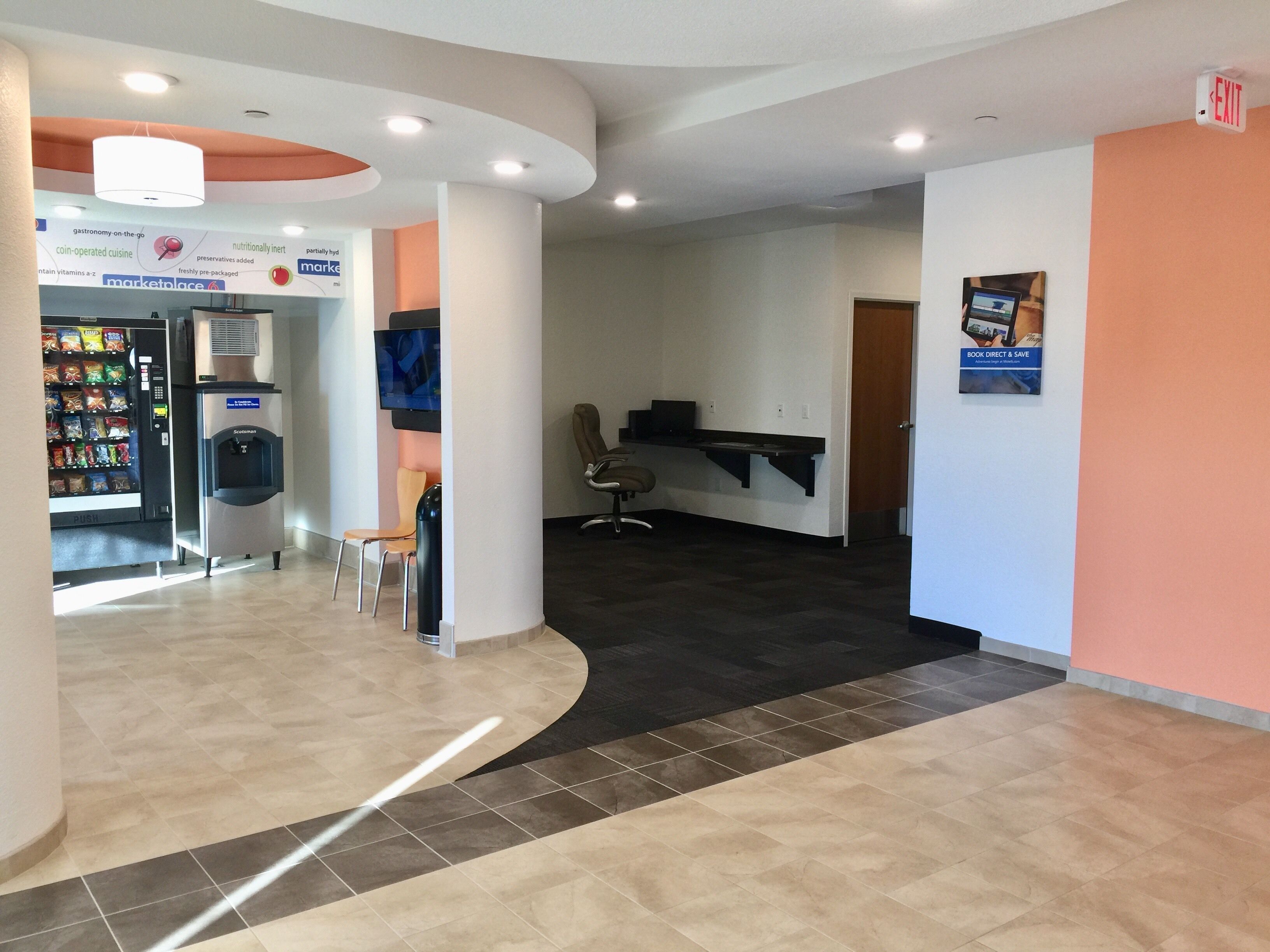 A modern lobby with a vending machine, seating area, and a reception desk.