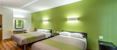 A hotel room with two beds, a small table, a chair, a mirror, and a trash bin.