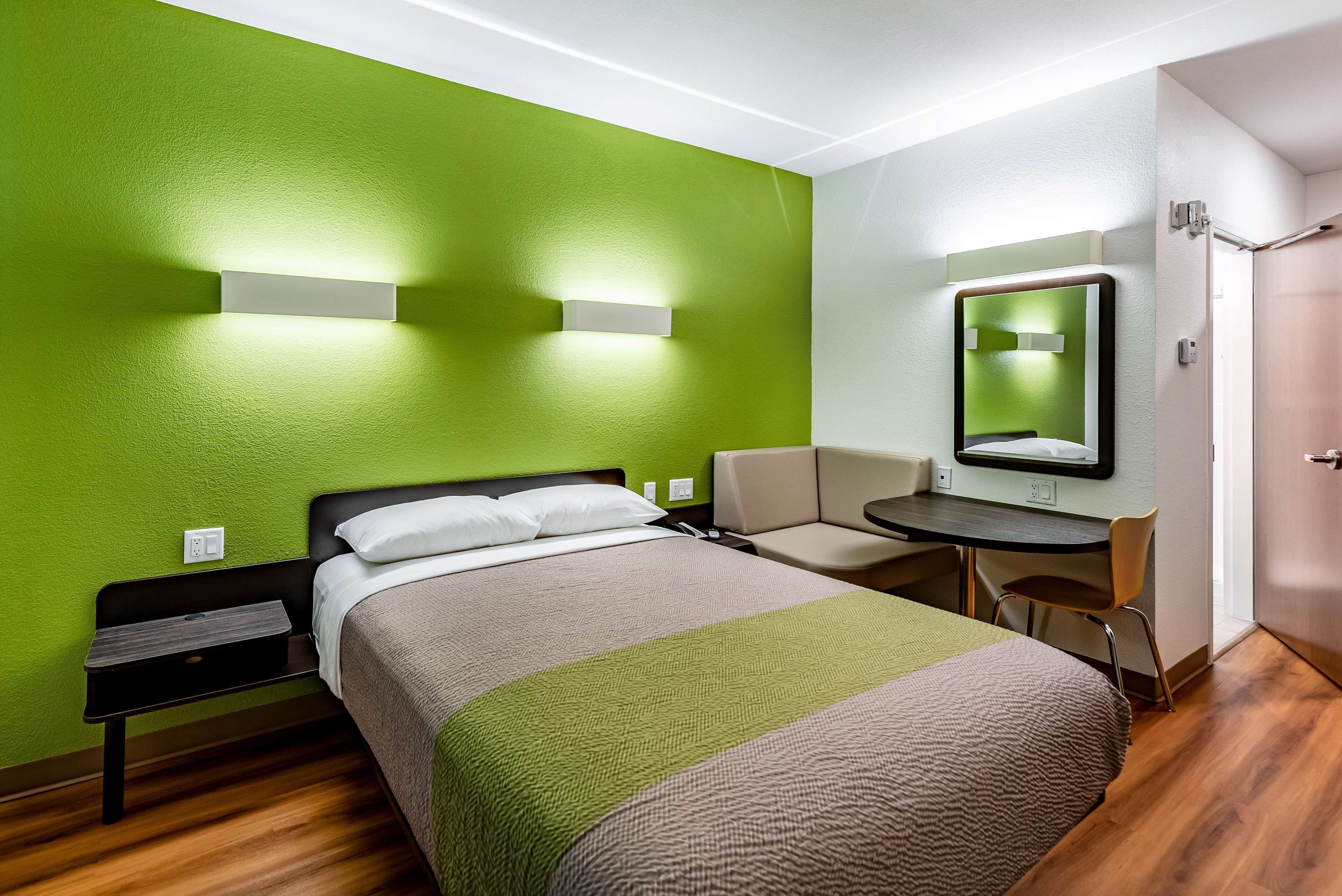 Una habitación de hotel con una cama, un escritorio, una silla y un espejo.