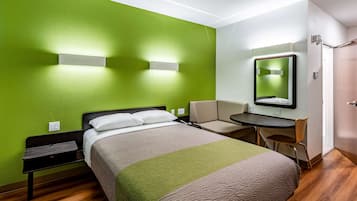 Una habitación de hotel con una cama, un escritorio, una silla y un espejo.