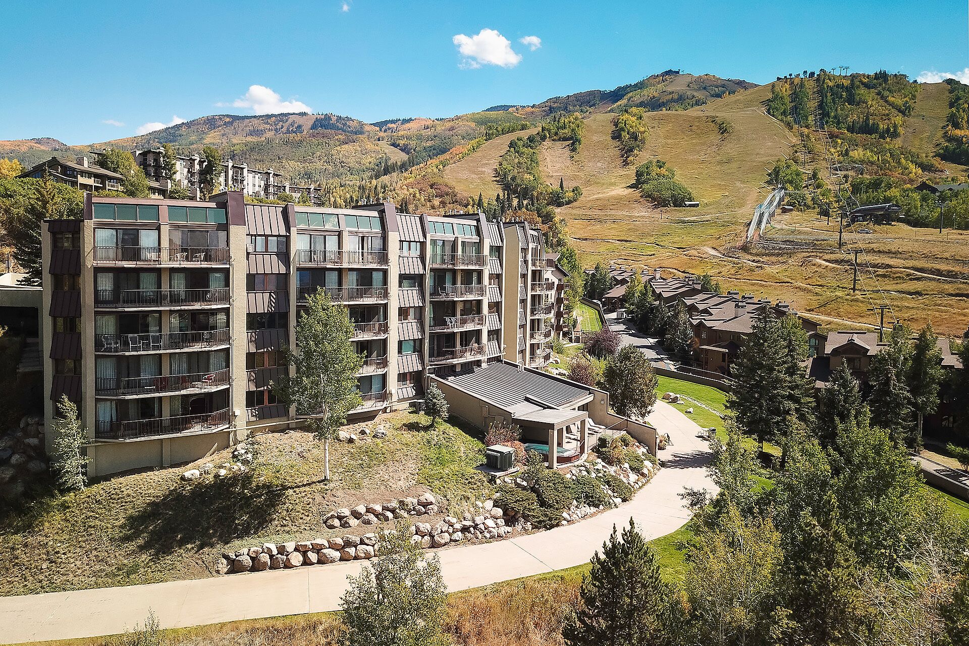 A multi-story hotel with balconies, a central courtyard, and a view of surrounding hills.