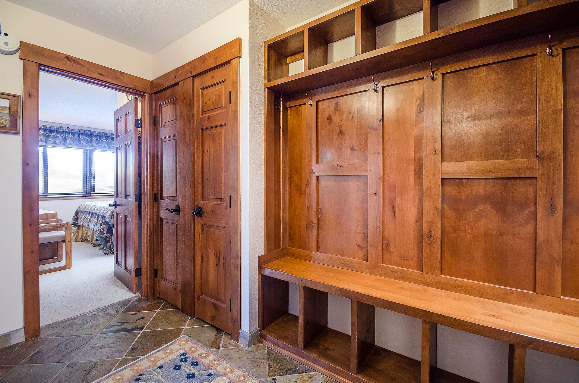A hallway with wooden doors and a bench.