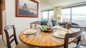 A dining area with a round wooden table set for four, surrounded by chairs. A painting of a cowboy on a horse is on the wall. - BT207 | Ski In | Great Views | Indoor Pool | Hot Tub | Winter Shuttle (Steamboat Springs)