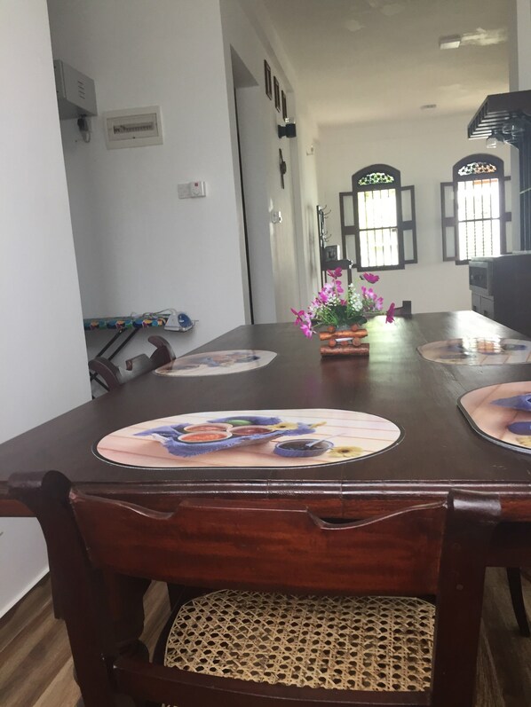 A dining table with placemats, chairs, and a vase of flowers.