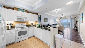A modern kitchen with white cabinetry, a built-in microwave, and a large island with a sink. - Gulf Views - Sleeps 6 | Gulf Shores | Direct Beach Access (Gulf Shores)