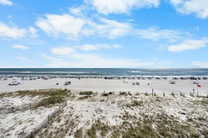 Uma praia com extensa faixa de areia e céu claro.