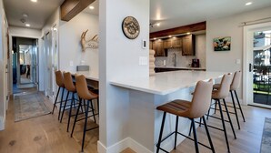 Una cocina moderna con una isla central, taburetes de bar de madera y un cráneo de alce decorativo.