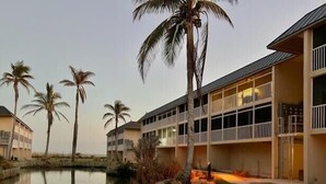 Een hotel met meerdere verdiepingen, een zwembad en palmbomen.