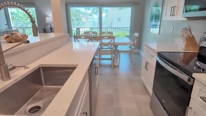 Een moderne keuken met een roestvrijstalen spoelbak, een eethoek met een witte tafel en stoelen, en een zwarte oven.