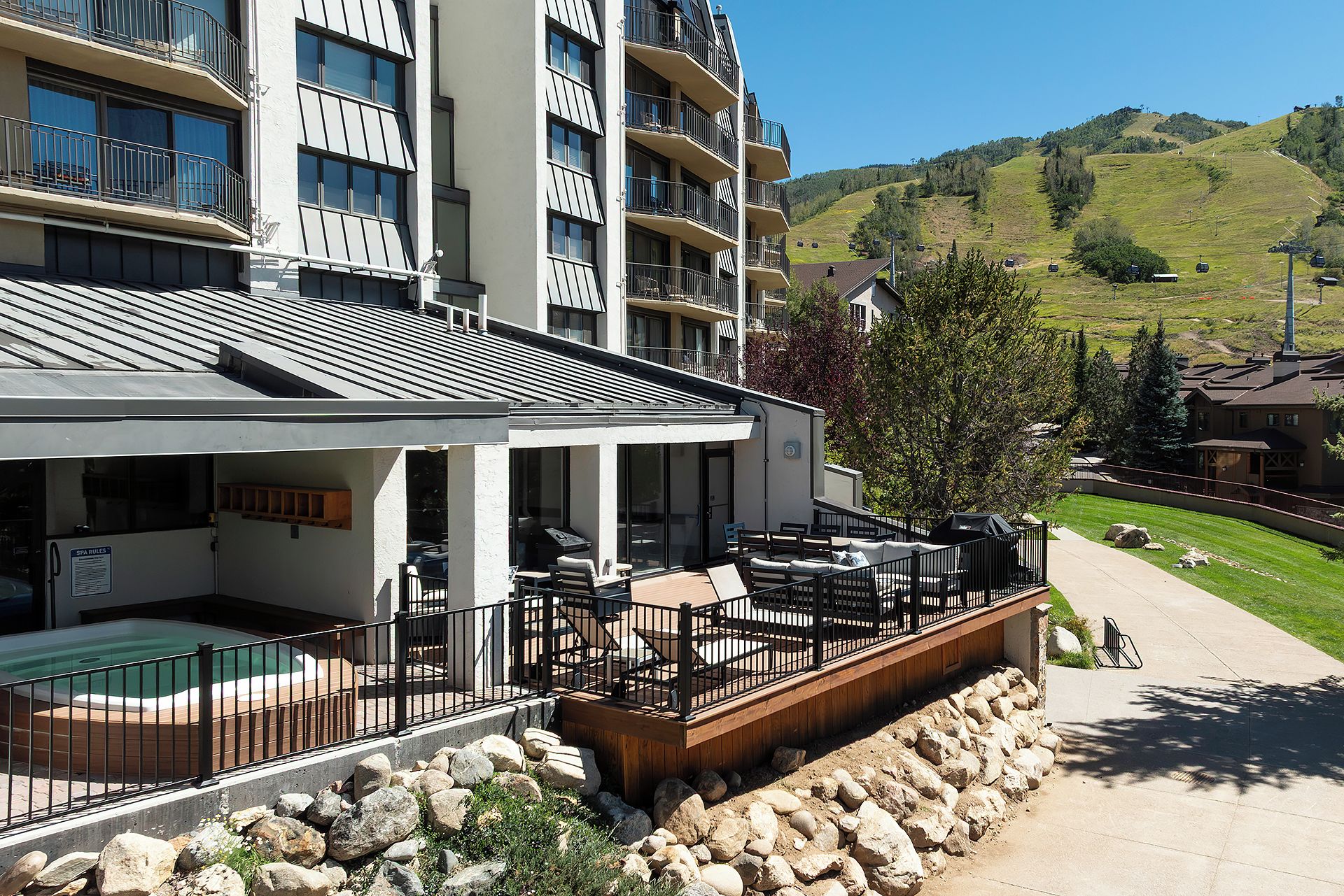 A hotel with a pool, outdoor seating, and a view of a hilly landscape.
