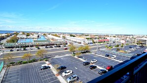 A parking lot with multiple cars, a swimming pool, and buildings in the background. - Fountainhead 702-Oceanfront 117th St, WIFI, Pool, Elev, W/D, AC (Ocean City)