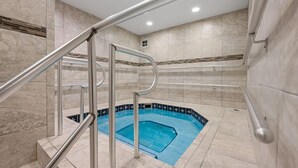 A swimming pool with a blue interior, surrounded by beige tiles and a metal handrail. - El Matador 414 by Alicia Hollis Rentals FREE TICKETS! $300/Day (Fort Walton Beach)