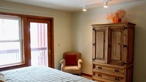A bedroom with a bed, a chair, a wooden cabinet, and a window with a view. - Hotel Style Room with Ski-In/Ski-Out Access (Whitefish)