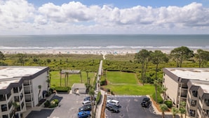 A view of a beach with a parking lot and buildings in the foreground.