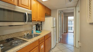 A kitchen with wooden cabinets, a microwave, a refrigerator, a stove, and a coffee maker.