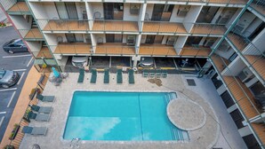 A multi-story building with a rooftop pool, outdoor seating, and a parking area.