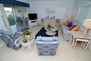 Een woonkamer met een bank, fauteuil, salontafel, televisie en decoratieve objecten.