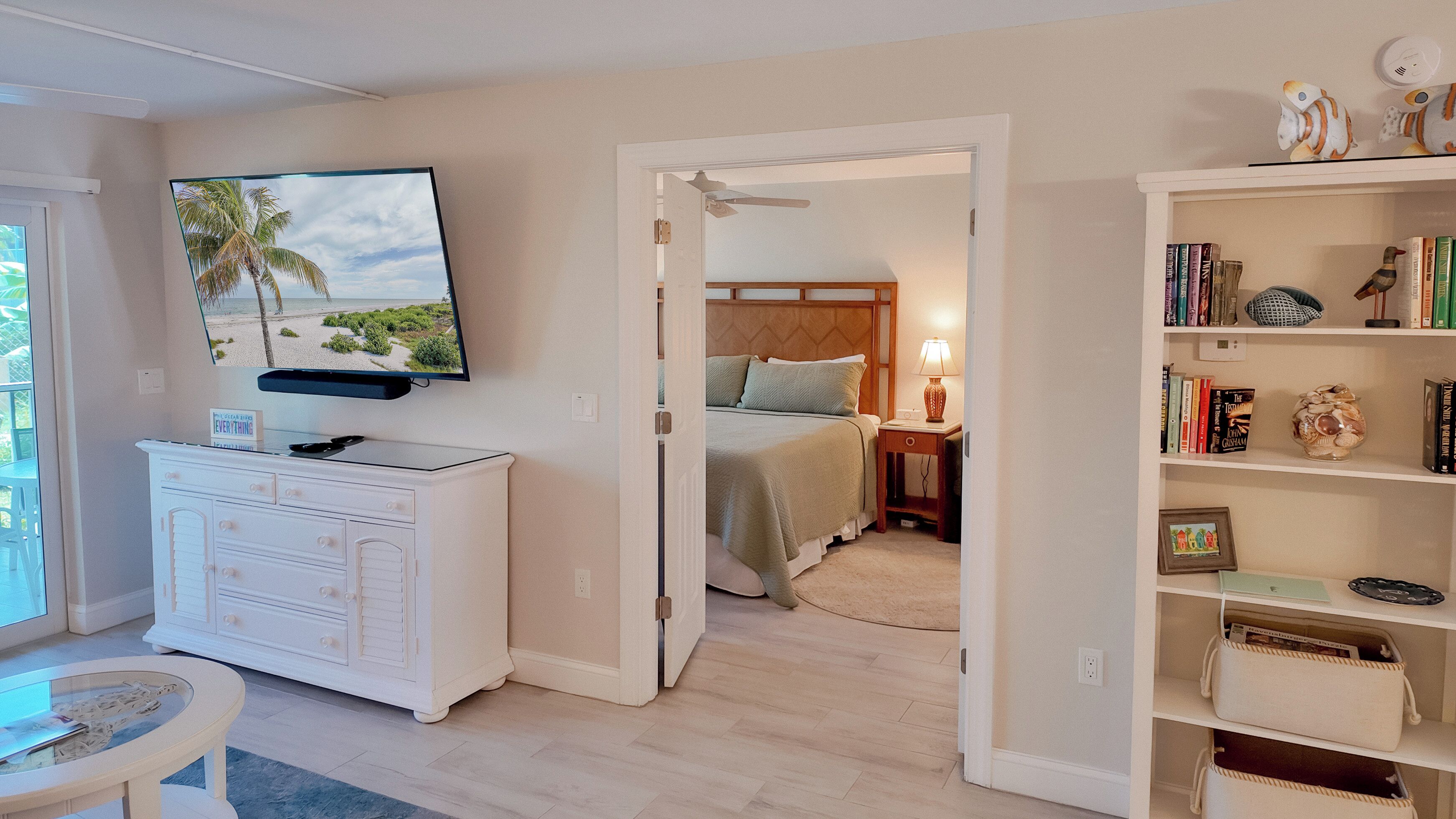 A bedroom with a bed, bedside table, lamp, and a TV mounted on the wall.