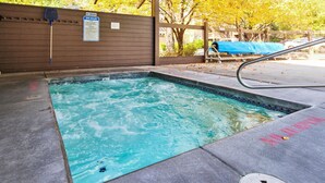 Un espace avec un jacuzzi, une terrasse en bois, un panneau interdisant de fumer et une bâche bleue sur une table.