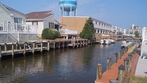 Un canal con pasarelas de madera, una torre de agua y casas adosadas a la orilla.